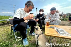 青空の下、おやつを待つパグとコーヒー片手にパグを見つめる男性