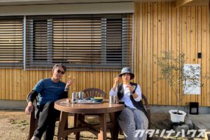 リノベーションで外壁を杉板に張りかえた住宅の前でお茶するスタッフ
