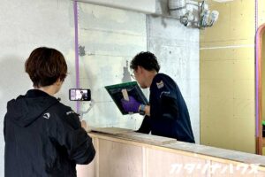 松山市の中古マンションリノベーション現場でキッチンのタイル施工を撮影するスタッフ