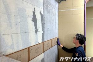 中古マンションのキッチン壁にオレンジ色のタイルを施工している様子
