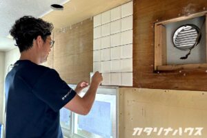 キッチンの壁に白いタイルを施工する様子