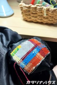 文字が薄くなったリュックのブランドタグを刺繍糸でダーニングしている様子。