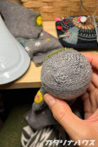 足裏が薄くなったグレーの靴下を、同系色の刺繍糸でダーニングして補強した様子。