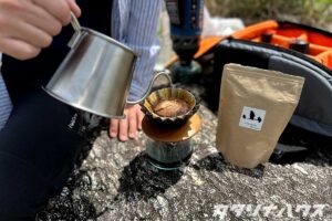 河原の岩の上でコーヒーをハンドドリップしている様子