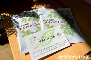 黄緑色がメインとなったデザインのドリップバッグと、店主の似顔絵が入ったショップカード