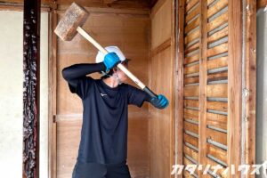 大きなハンマーを持ち壁を解体する男性